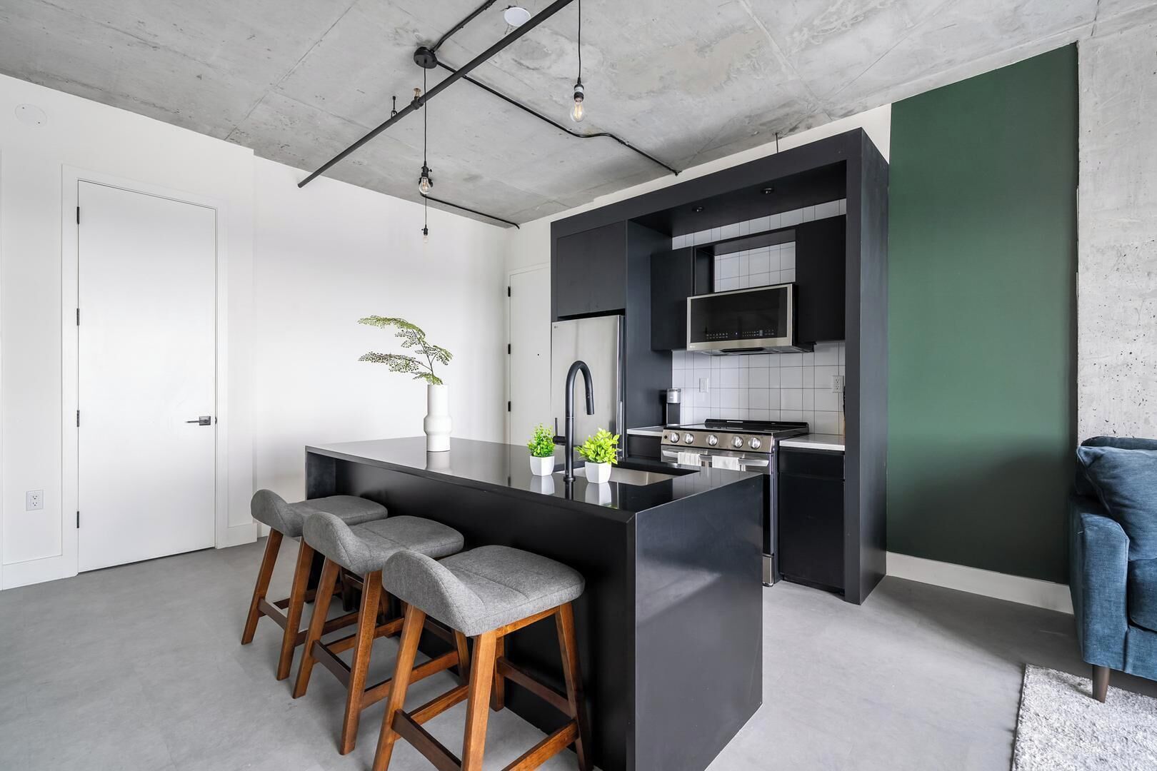 Una cocina moderna con una isla central, taburetes de bar, microondas y estufa.
