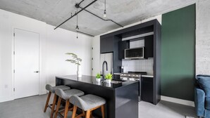 Una cocina moderna con una isla central, taburetes de bar, microondas y estufa.