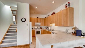 Une cuisine moderne avec des meubles en bois, un îlot central blanc et un four à micro-ondes.