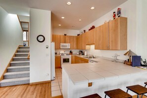A modern kitchen with wooden cabinets, a white island, and a microwave. - Savoy Villas 4B, Vail Top Floor 3BD Condo With Views (Vail)
