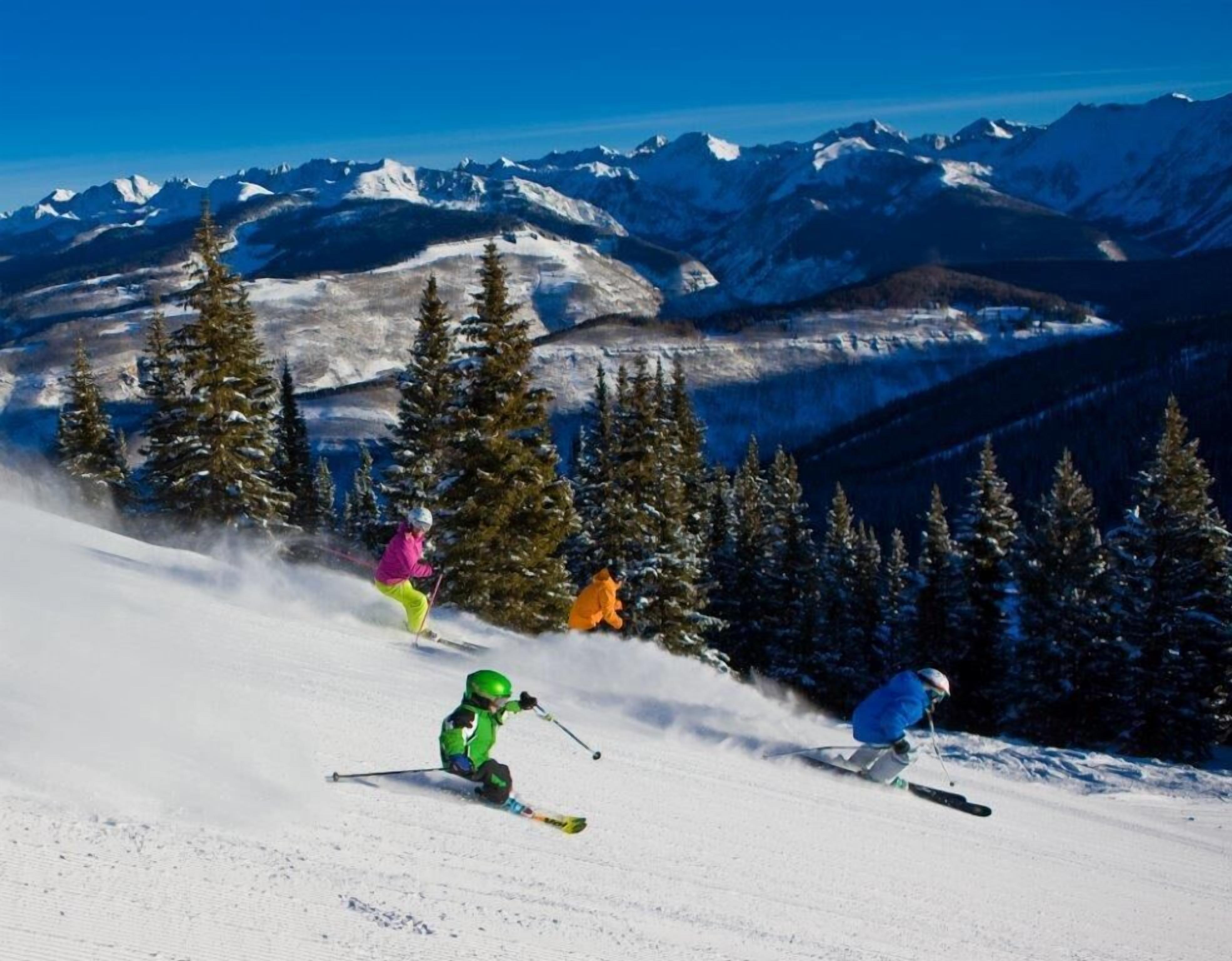 A ski slope with skiers and a mountainous backdrop.