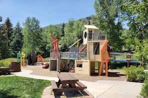 A playground with a slide, climbing structures, and a picnic table. - Savoy Villas 4B, Vail Top Floor 3BD Condo With Views (Vail)