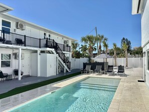 A two-story building with a pool, outdoor seating, and a white fence. - CWB Retreats at Bayside View 4 - 1 Studio (Clearwater)