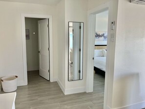 A hotel room with a bed, a large mirror, and a door leading to another room. - CWB Retreats at Bayside Suite 2 & View 3 (Clearwater)