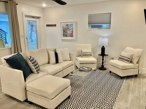 A living room with a sectional sofa, a small round table, a floor lamp, and a patterned rug. - CWB Retreats at Bayside Suite 2 & View 3 (Clearwater)