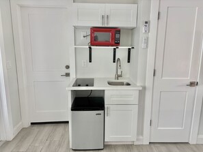 Eine kleine Küchenzeile mit Mikrowelle, Spüle und kleinem Kühlschrank.