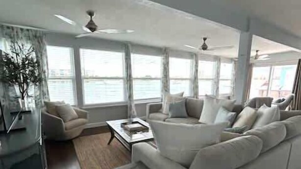 Una sala de estar moderna con un sofá blanco, una mesa de centro de vidrio y vista al mar a través de amplios ventanales.