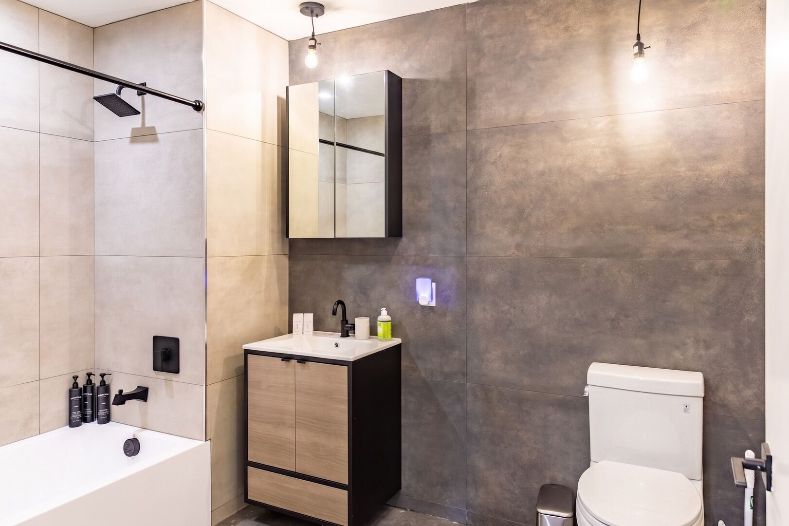 Un baño moderno con bañera, lavamanos con espejo e inodoro.