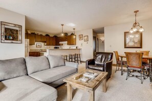 A living room with a sofa, coffee table, and dining area with chairs and a table. - Scorpio 304, 2BD Vail Condo With Wood Fireplace (Vail)
