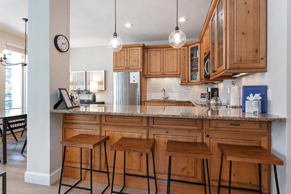 A kitchen with wooden cabinets, a stainless steel refrigerator, and a granite countertop. - Sun Vail 11b, 3BD Condo (Vail)