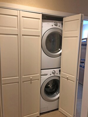 A laundry room with two stacked front-loading washers and dryers, white cabinetry, and a carpeted floor. - Sun Vail 11b, 3BD Condo (Vail)