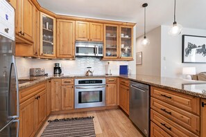 A kitchen with wooden cabinets, stainless steel appliances, and a granite countertop. - Sun Vail 11b, 3BD Condo (Vail)