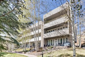 A multi-story building with balconies, outdoor seating, and a landscaped area with trees. - Sun Vail 22d, 2BD Condo With Vail Mountain Views (Vail)
