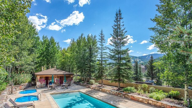 A pool area with lounge chairs, a small gazebo, and a view of mountains. - Sun Vail 34b, 3BD Condo With Vail Mountain Views (Vail)