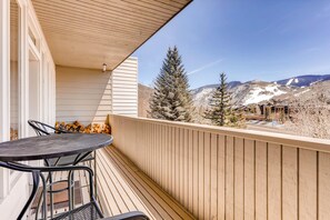 Ein Balkon mit Blick auf schneebedeckte Berge, einem Holzgeländer und einem Tisch mit Stühlen.