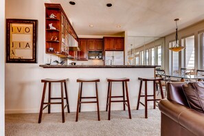 Eine Küche mit Holzschränken, einem Edelstahlkühlschrank und einer Bar mit Barhocker.