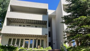 A multi-story building with a flat roof, a front entrance with steps, and a small garden area with grass and plants. - Sun Vail 34b, 3BD Condo With Vail Mountain Views (Vail)