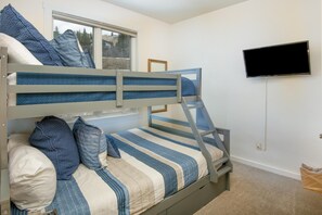 Ein Stockbett mit blauer Bettwäsche, ein Fernseher an der Wand und ein Fenster mit Blick.