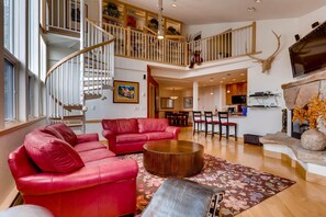 A spacious living area with a red sofa, a round coffee table, and a staircase leading to a loft. - Tyrolean 5, 3BD Condo in Vail Village (Vail)