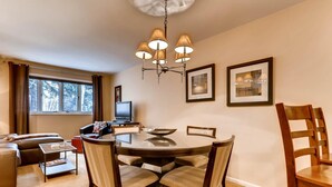 A dining area with a round table, chairs, a chandelier, and framed pictures on the wall. - Vail Trails East 5B, 1BD Condo on East Side of Vail Village (Vail)