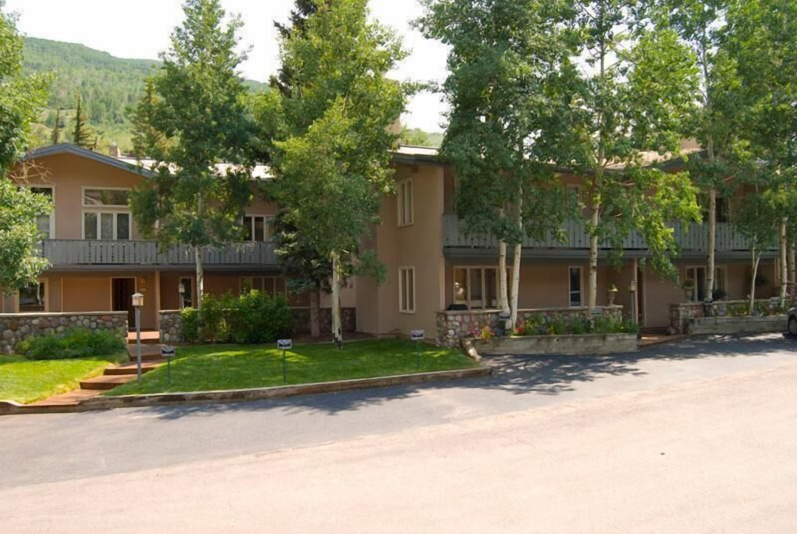 A multi-story building with a stone facade, multiple balconies, and a well-maintained lawn.
