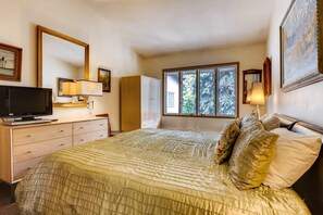 A bedroom with a bed, a TV, a dresser, a window, and a door. - Vail Trails East 6, 2BD + Loft Condo on East Side Vail Village (Vail)