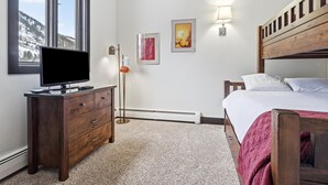 Quarto com cama, televisão em uma cômoda, aquecedor e quadros nas paredes.
