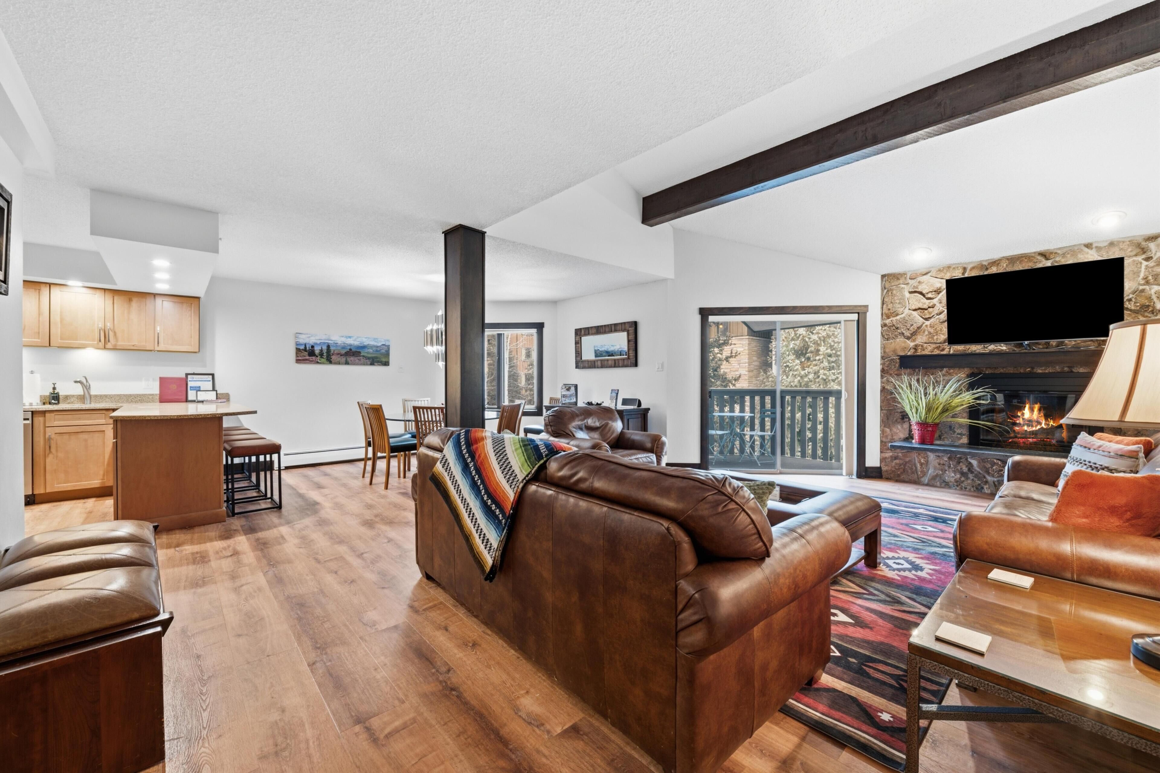 A spacious living room with a brown leather sofa, a wooden coffee table, and a fireplace.