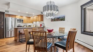 A modern kitchen with stainless steel appliances, wooden cabinets, and a dining area with a glass table and chairs. - Westwind 407 3BD 2BA Gold Condo in Vail Lionshead Village (Vail)