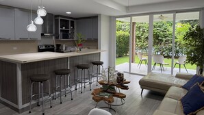 A modern kitchen with a central island, bar stools, and a dining area with a sofa and chairs. - Apartment in Playa Herradura (Herradura)