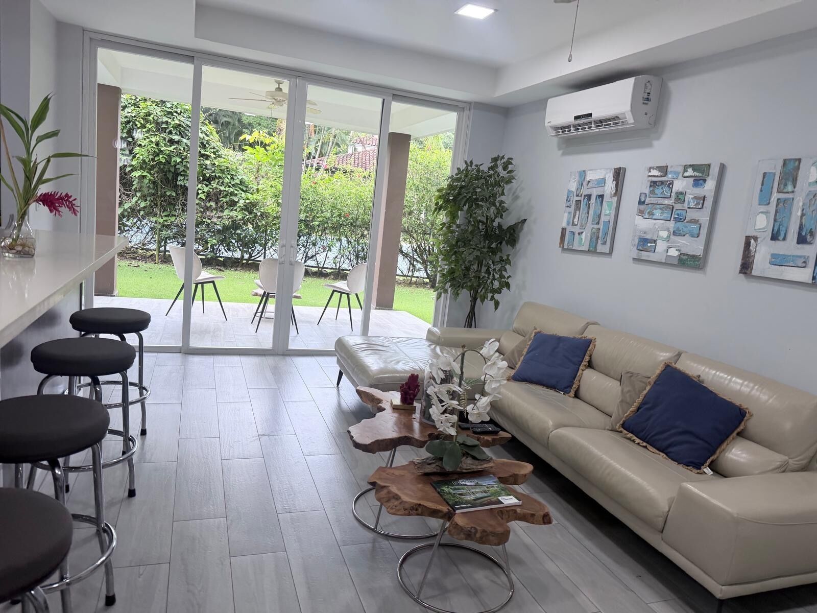 A modern living room with a sofa, coffee table, and bar stools.