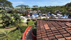 A resort with multiple swimming pools, lush greenery, and a view of the sea. - Apartment in Playa Herradura (Herradura)