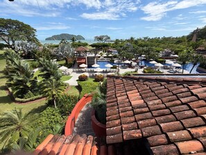 A resort with multiple swimming pools, lush greenery, and a view of the sea. - Apartment in Playa Herradura (Herradura)