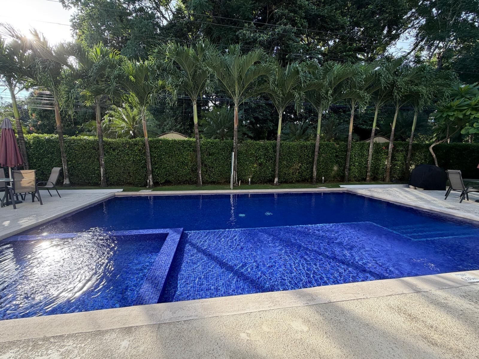 A rectangular swimming pool with clear blue water, surrounded by a concrete deck.