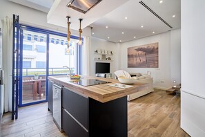 Cozinha moderna com ilha de madeira, eletrodomésticos embutidos e área de jantar com vista para o exterior.