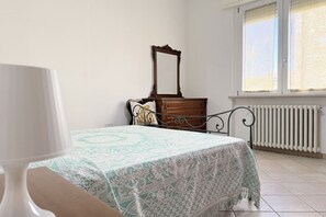 A bedroom with a bed, dresser, mirror, and radiator.