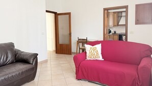 Una sala de estar con un sofá rojo, un sofá de cuero marrón y un comedor con mesa y sillas.
