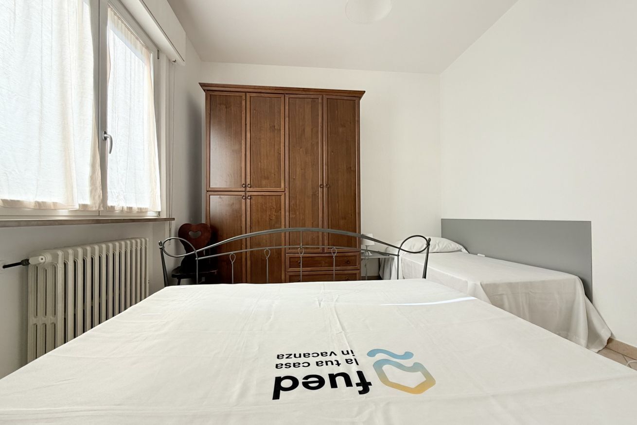 A bedroom with a bed, two bedside tables, a wardrobe, and a radiator.