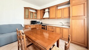 Una cocina con armarios de madera, una mesa de comedor y un sofá azul.