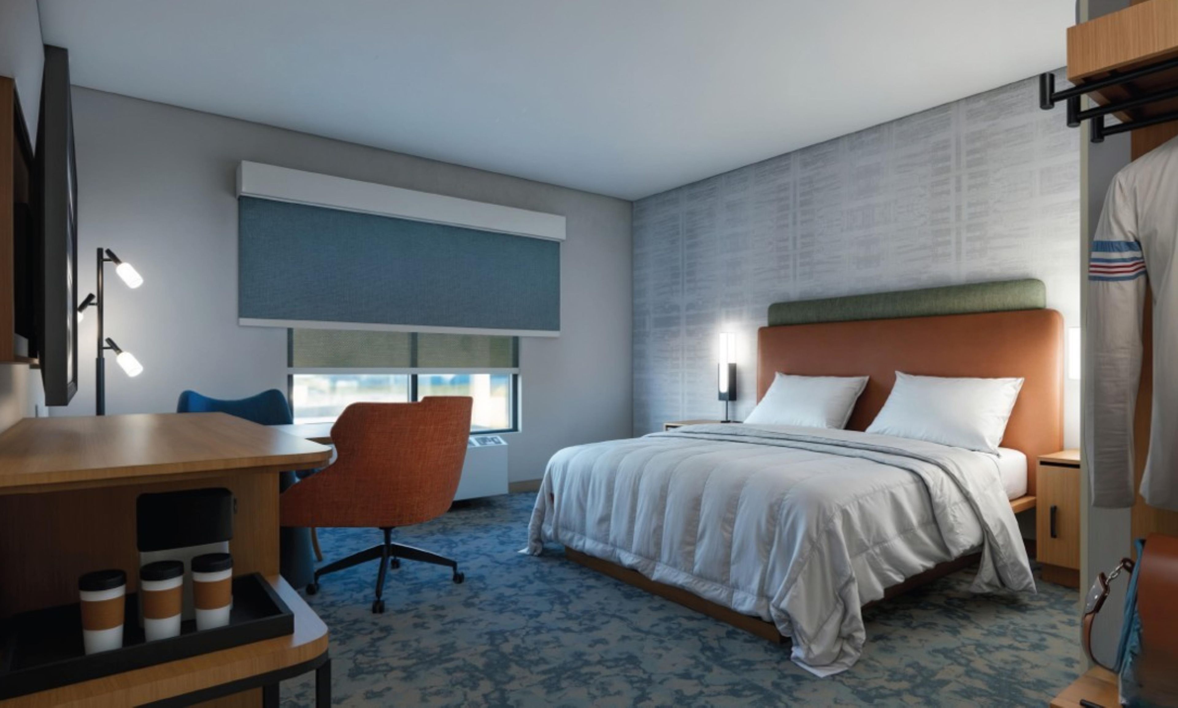 Une chambre d’hôtel comprenant un lit, un bureau avec une chaise, une fenêtre et un mur orné d’un motif texturé.
