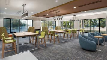 Une salle de réunion moderne, équipée de tables, de chaises et d’une grande fenêtre.