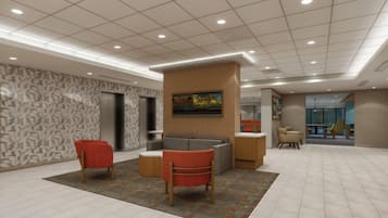 Un hall d’entrée avec un comptoir de réception, deux fauteuils rouges, un canapé gris, des murs à motifs et un plafond doté d’un éclairage encastré.