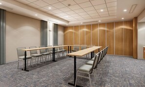 A conference room with a long table, chairs, a patterned carpet, wooden panel walls, and a cross on the window. - Hampton Inn By Hilton Manhattan Aggieville (Manhattan)