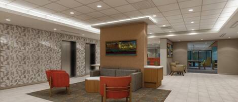 A lobby with a reception desk, two red chairs, a gray sofa, patterned walls, and a ceiling with recessed lighting.