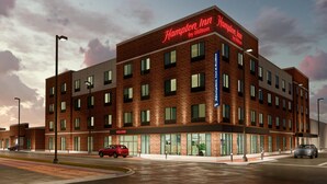 A Hampton Inn by Hilton hotel with a brick facade, multiple windows, and a 'Welcome' sign. - Hampton Inn By Hilton Manhattan Aggieville (Manhattan)