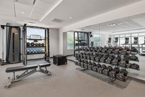 Ett modernt gym med utrustning för styrketräning, löpband och en vägg med speglar.