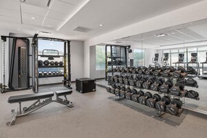 A modern gym with weightlifting equipment, treadmills, and a mirrored wall.