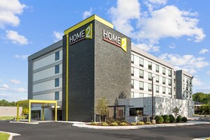 Un moderno edificio de hotel con un llamativo letrero 'HOME 2', múltiples ventanas y un exterior bien cuidado.