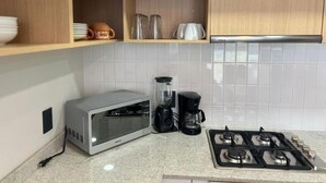 A kitchen with a microwave, coffee maker, and gas stove. - Livify (Zapopan)