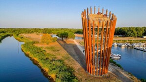 Une tour au design unique, dotée d’une plateforme d’observation, et entourée d’une rivière paisible et de verdure.